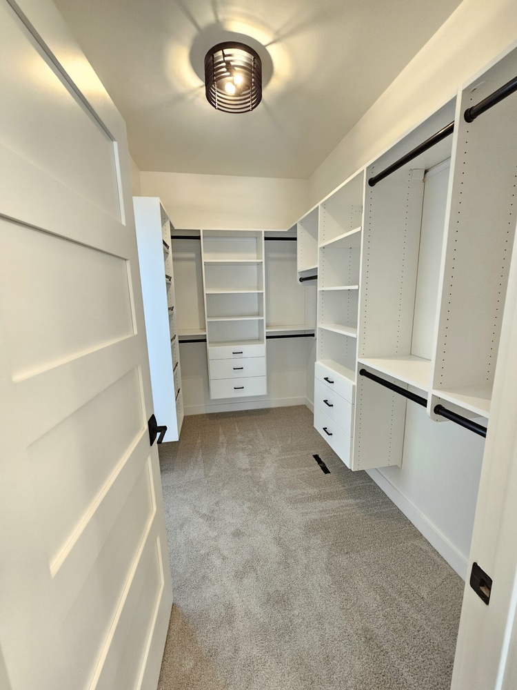 Walk-in closet with built-in drawers and rods in Kaukauna home by Midwest Design Homes