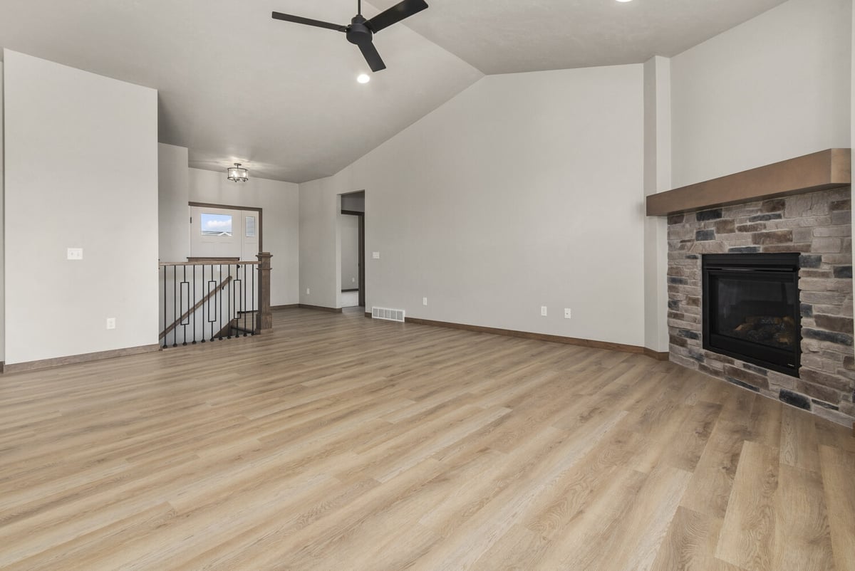 Open living room with stone fireplace and staircase in custom home by Midwest Design Homes