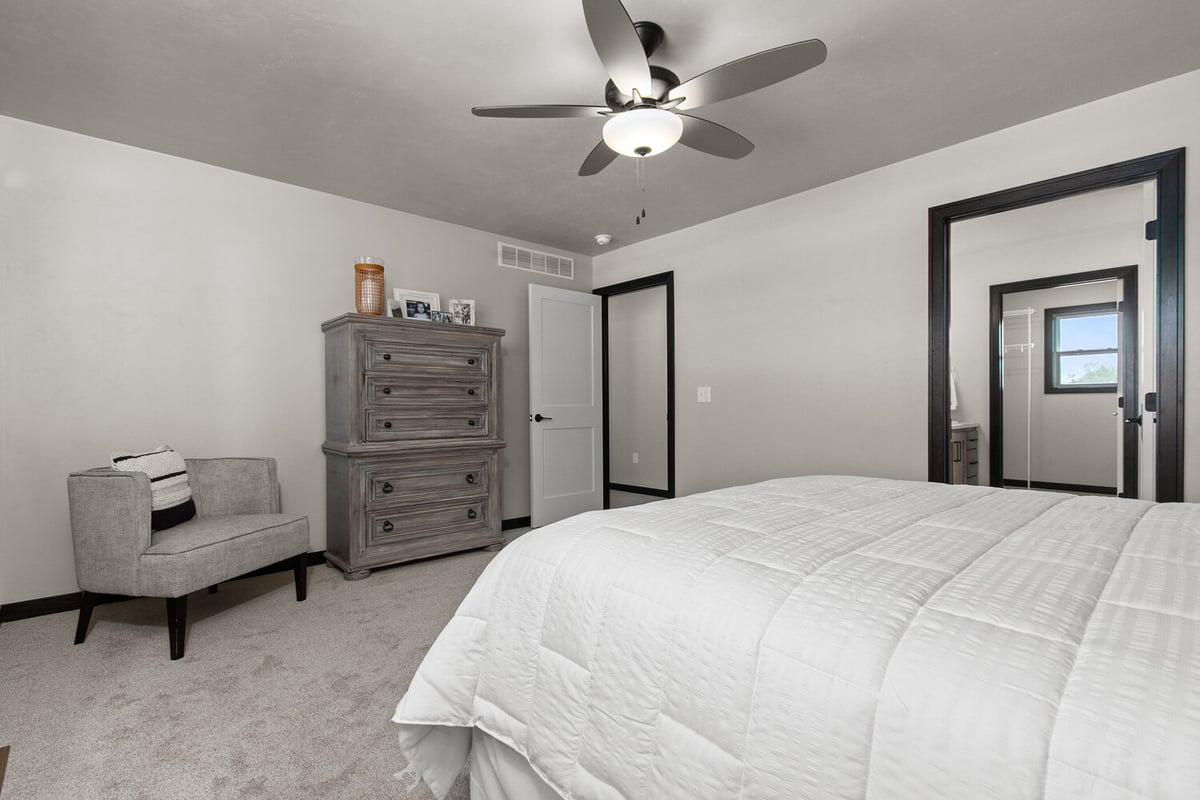 Bedroom with white walls and ceiling fan by Midwest Design Homes in Harrison, Wisconsin