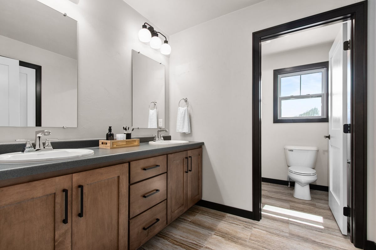 Midwest Design Homes custom-built bathroom with side-by-side mirrors and natural wood cabinet