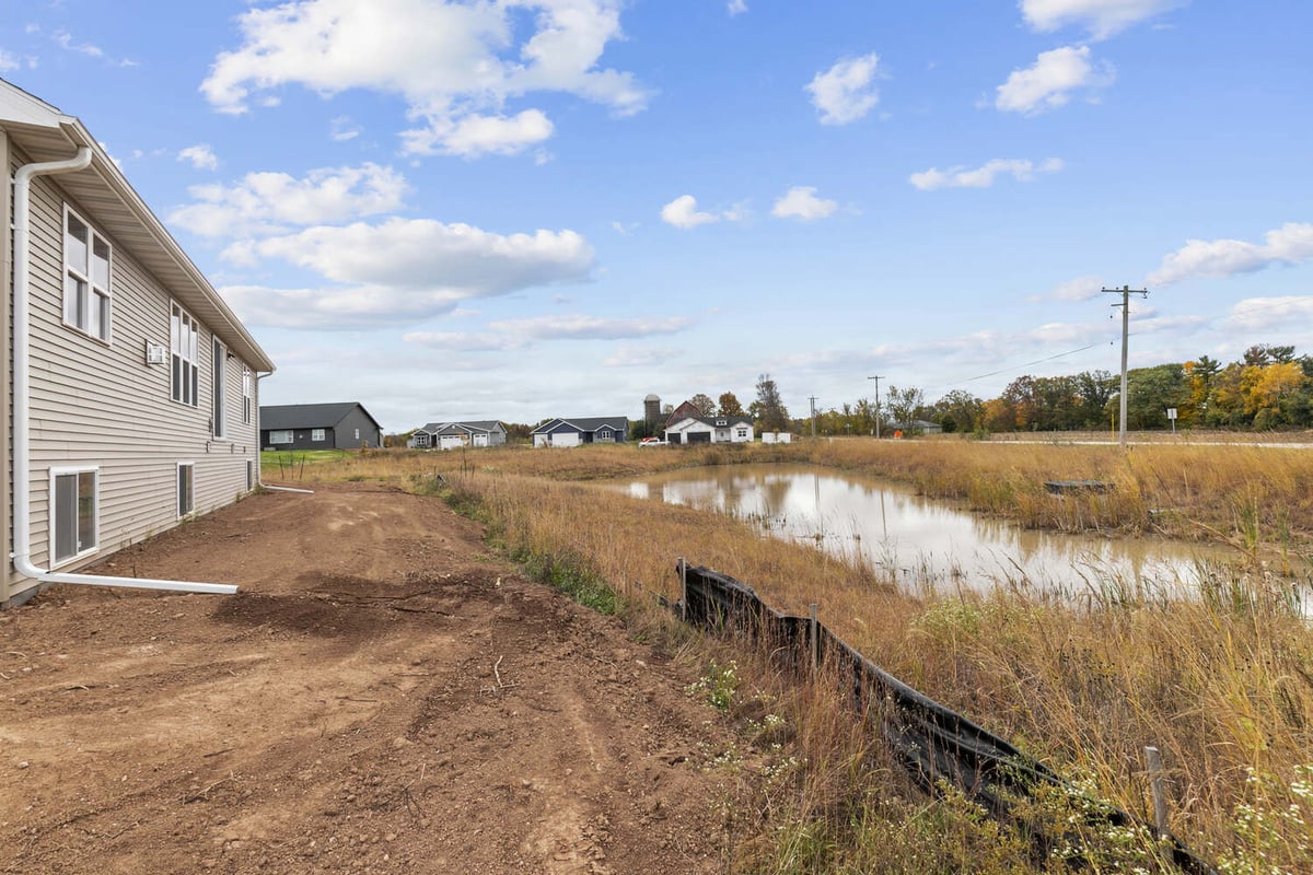 Backyard of custom Wisconsin home by Midwest Design Homes with pond view