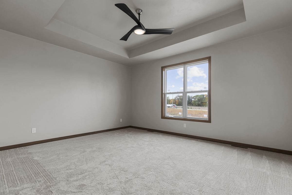 Bedroom with large window and tray ceiling in Midwest Design Homes custom home, Kaukauna, WI