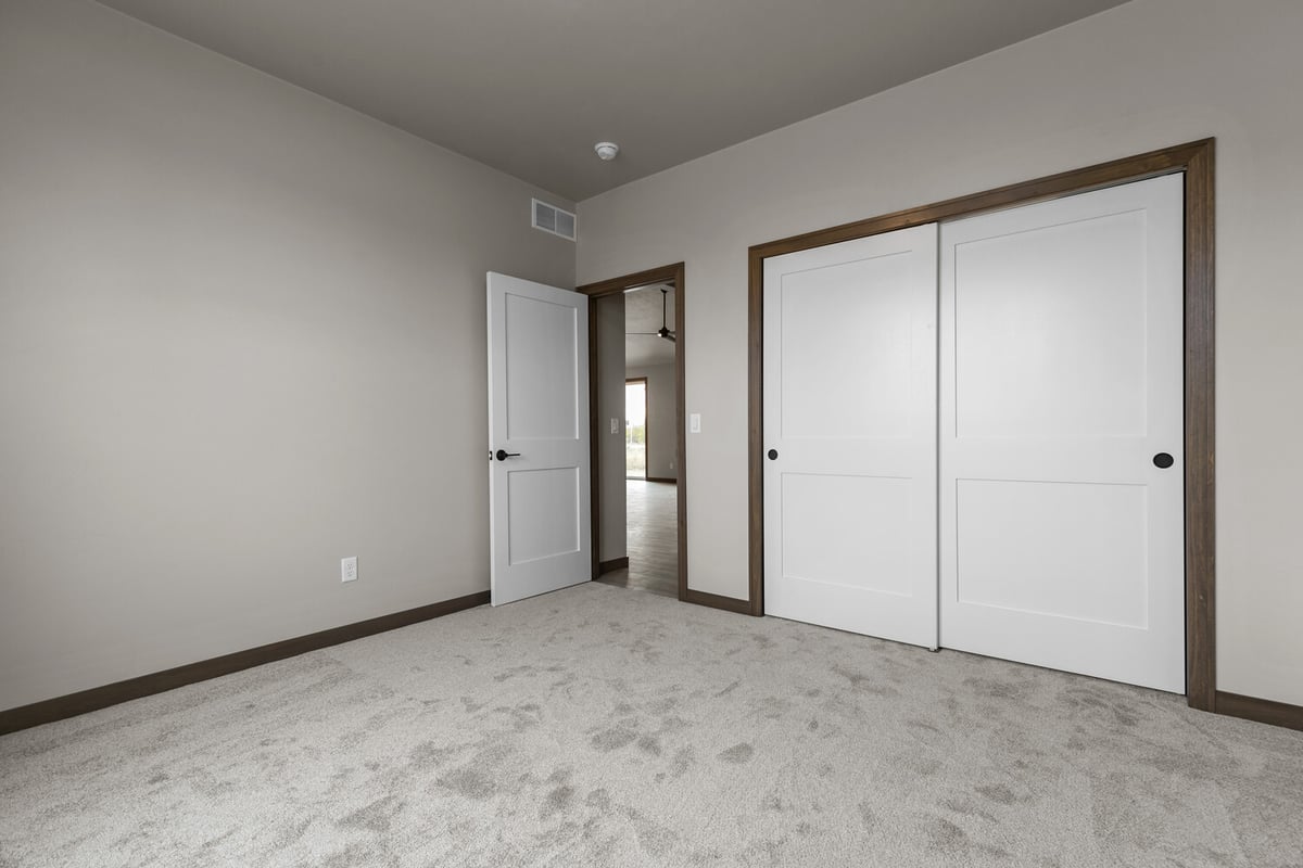 Carpeted bedroom with sliding closet doors in a Midwest Design Homes custom home in Green Bay, WI