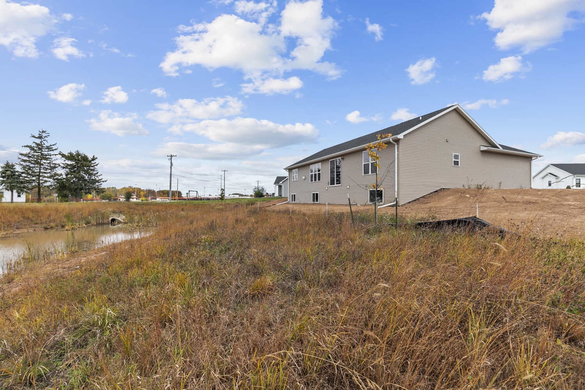 Custom home backyard in Appleton WI by Midwest Design Homes near pond and field