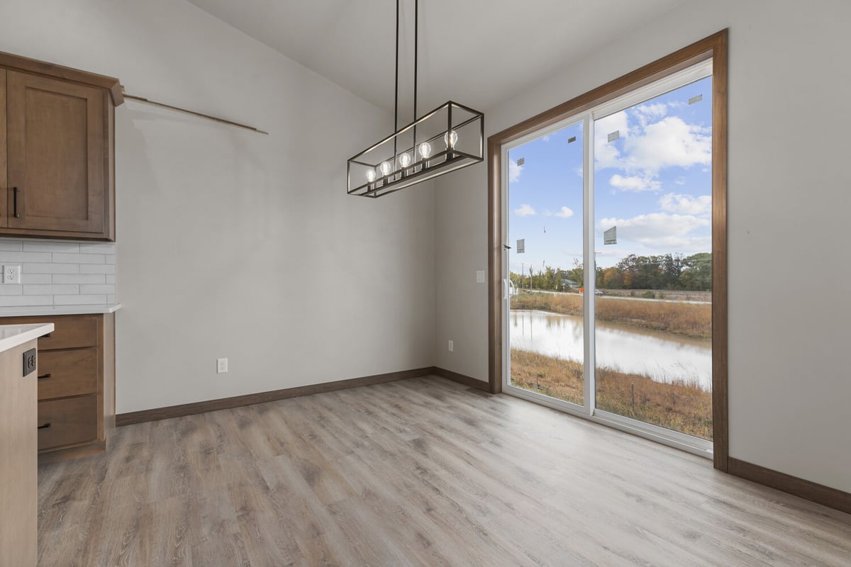 Dining area with modern light and patio door in a custom home by Midwest Design Homes