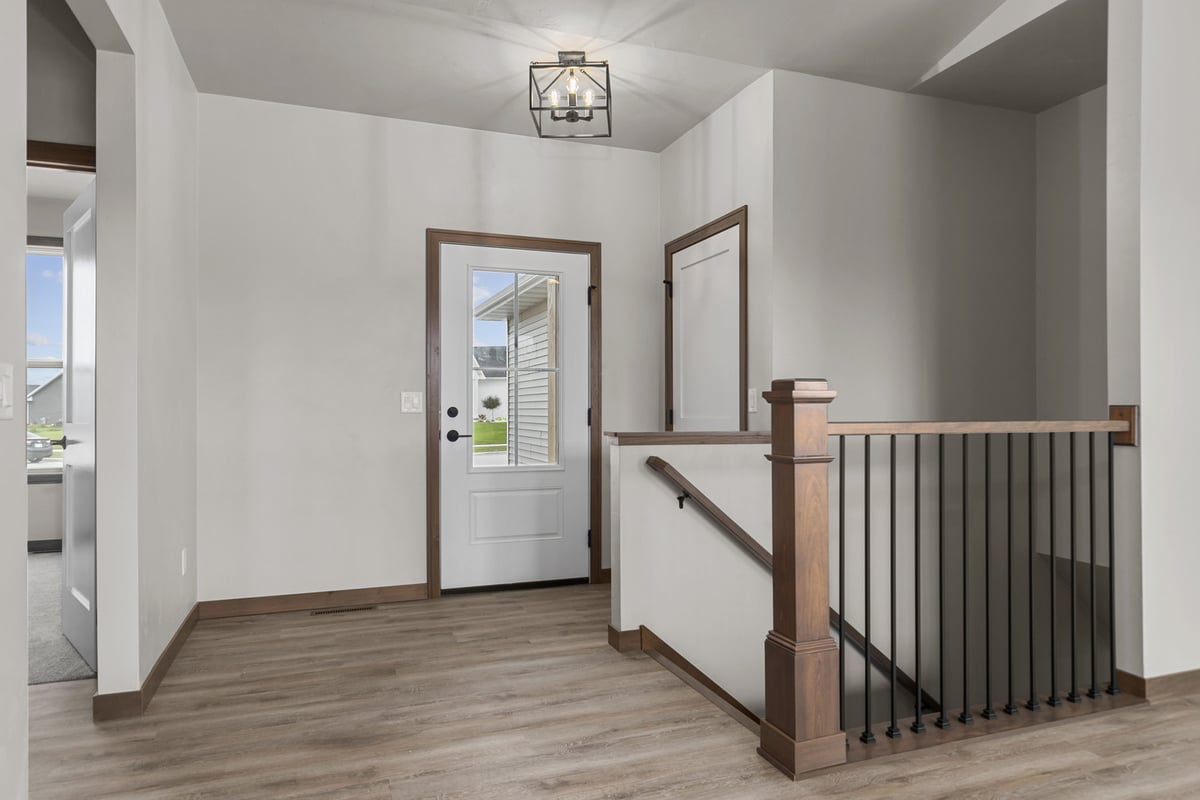 Entryway and staircase with wood railing in a Midwest Design Homes custom home in Fremont, WI