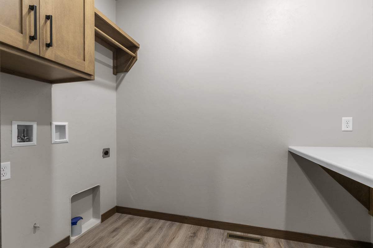 Functional laundry area with upper cabinets in a Midwest Design Homes home in Ellington