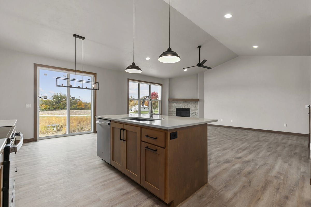 Kitchen island with lighting and fireplace view in a custom home by Midwest Design Homes