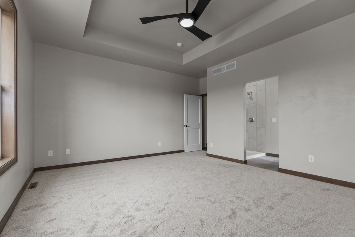 Master bedroom with tray ceiling and open shower view in custom home by Midwest Design Homes
