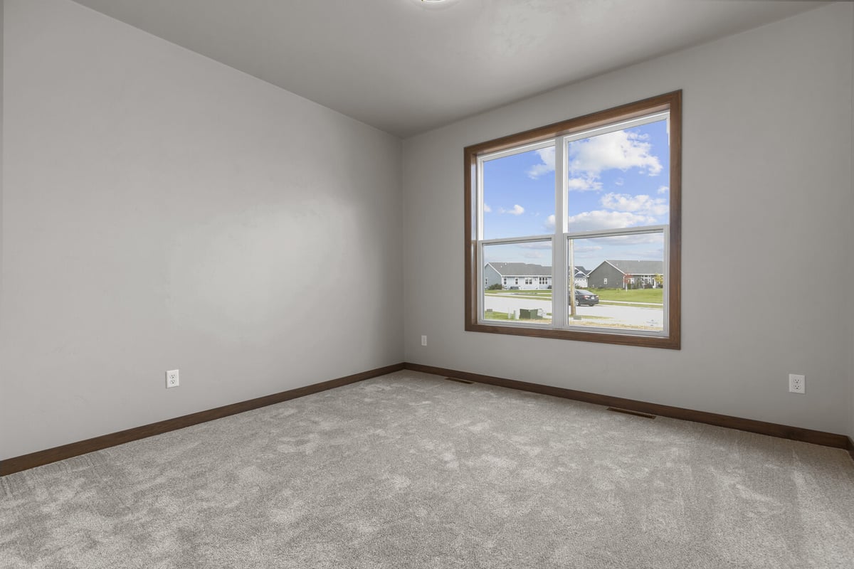 Sunlit front bedroom with large window in a Midwest Design Homes custom home in Bellevue, WI