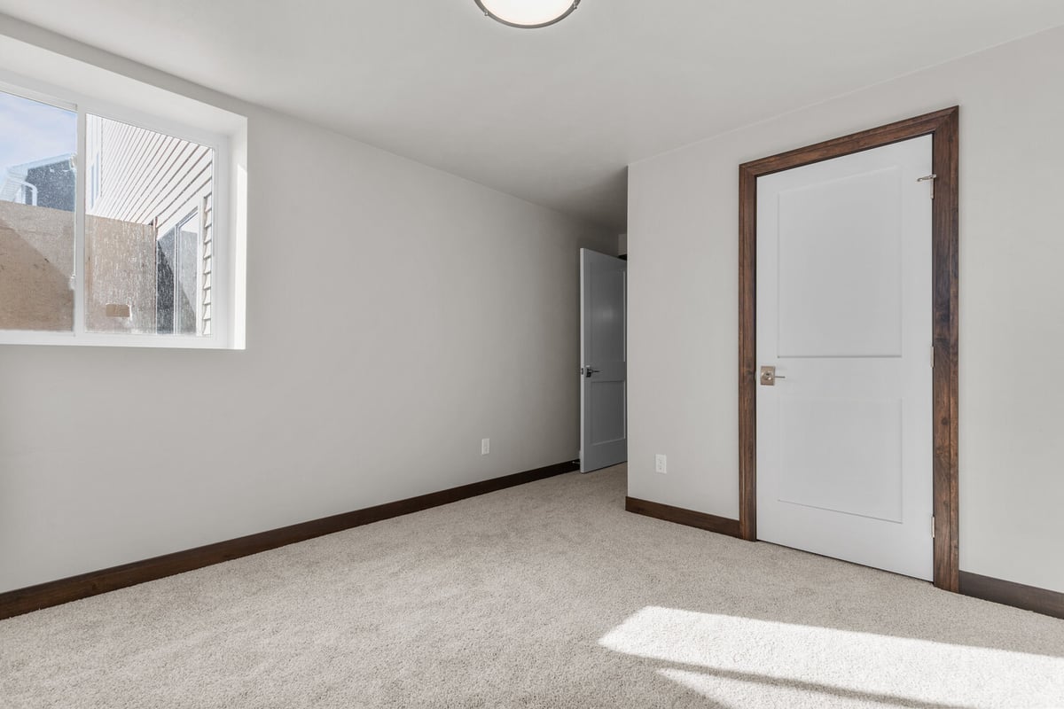 Carpeted bedroom in custom Kaukauna home by Midwest Design Homes with bright egress window