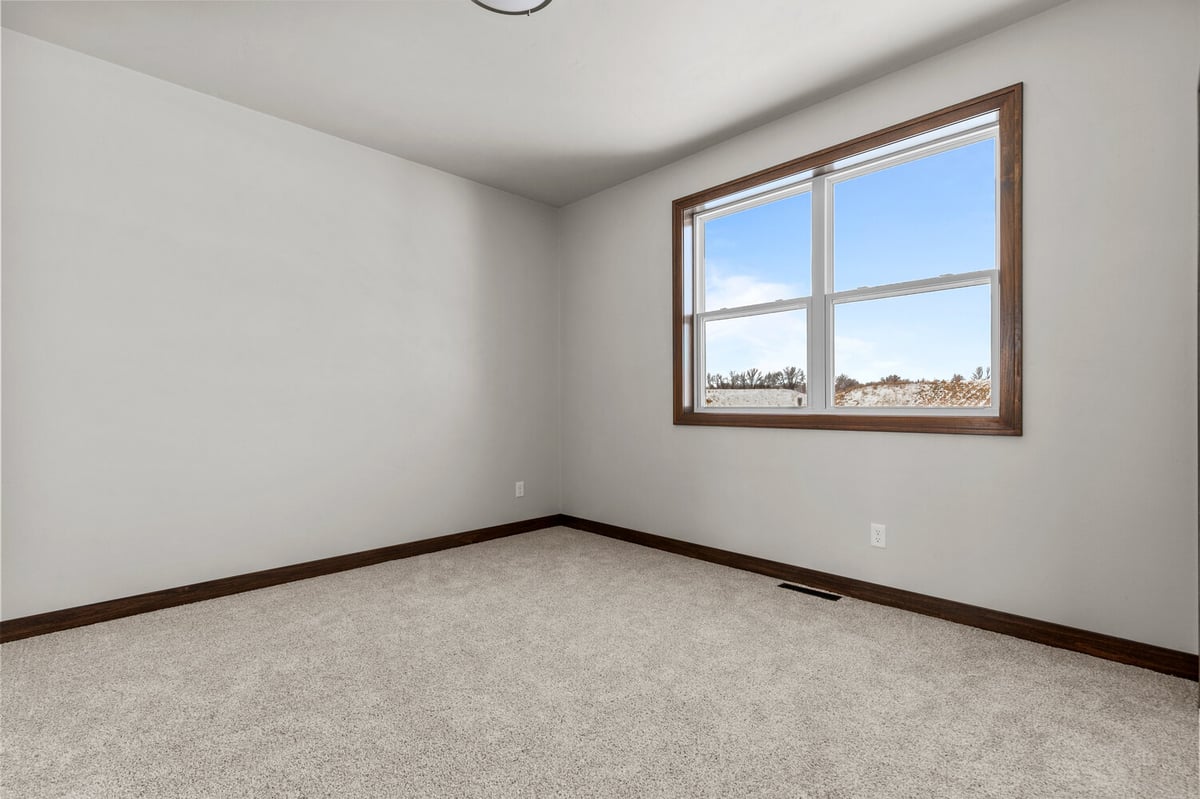 Carpeted bedroom with large window in Kaukauna home by Midwest Design Homes
