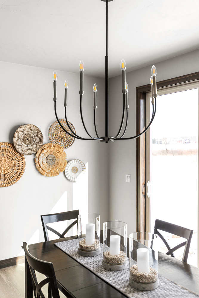 Dining space with chandelier and woven wall decor in Kaukauna home by Midwest Design Homes