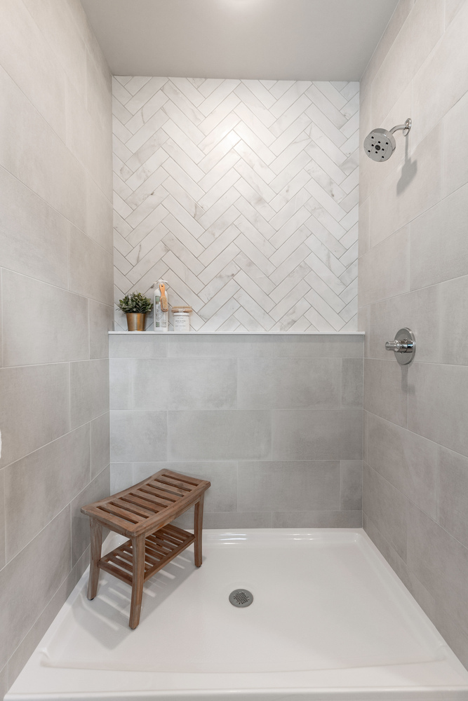 Herringbone tile shower with bench in custom Kaukauna, WI home by Midwest Design Homes