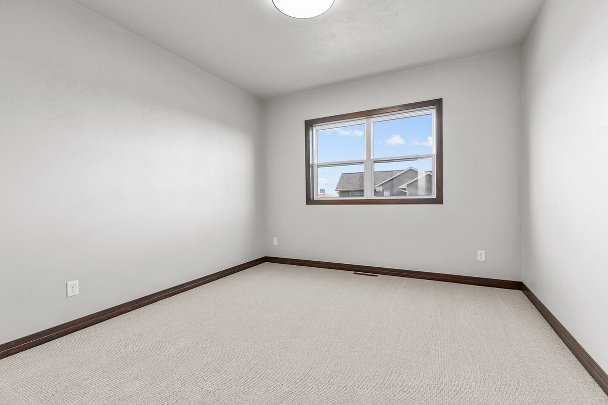Quiet carpeted bedroom with window in new Wisconsin custom home by Midwest Design Homes