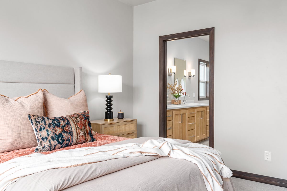 Soft bedding and wood furniture in bedroom by Midwest Design Homes in Kaukauna, WI