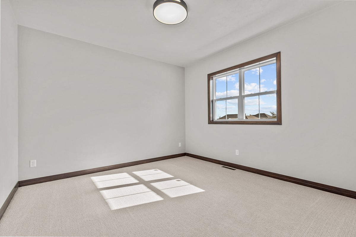 Sunlit bedroom with large window in Wisconsin home by Midwest Design Homes