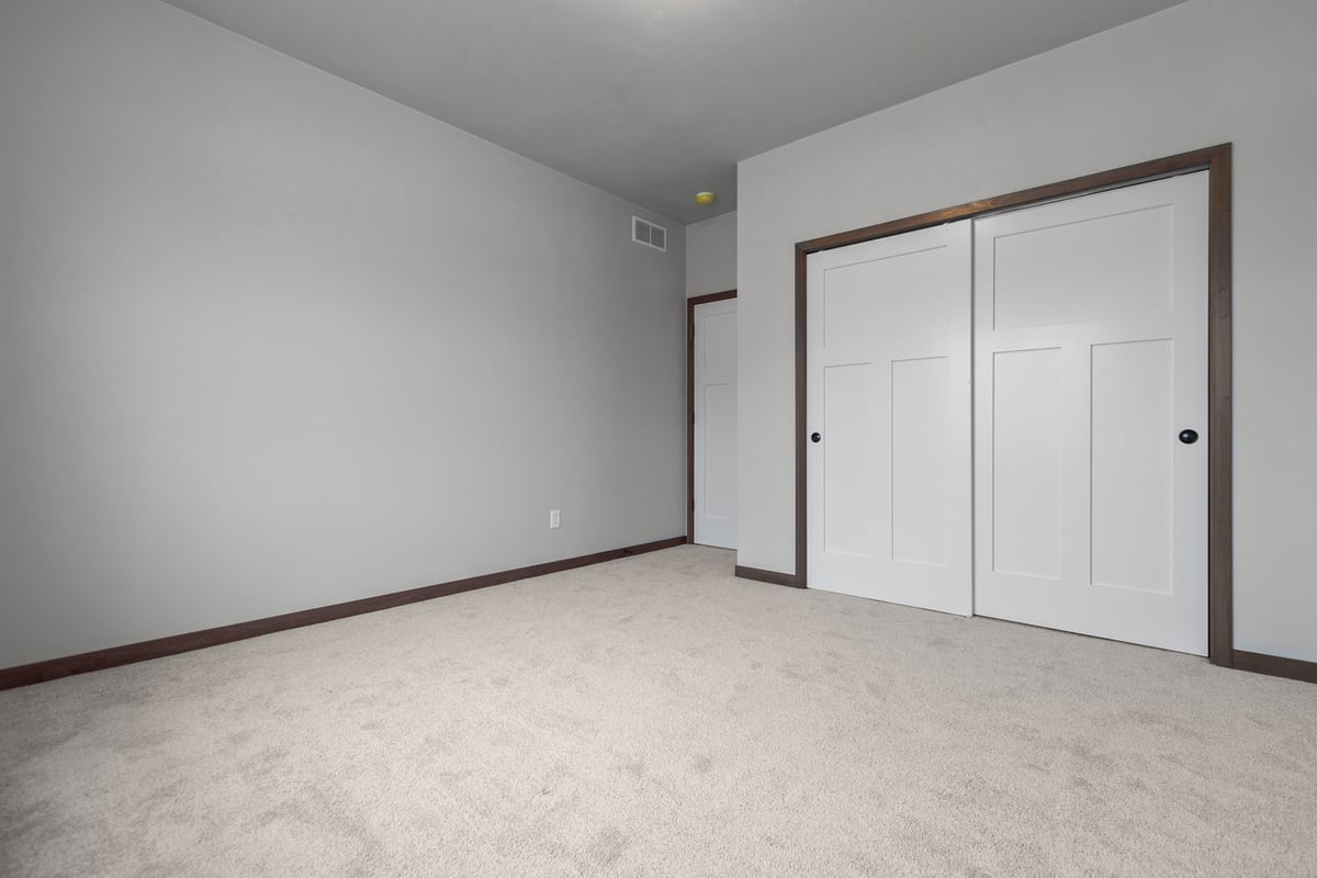 Carpeted bedroom with double closet doors in a Fox Cities custom home by Midwest Design Hom