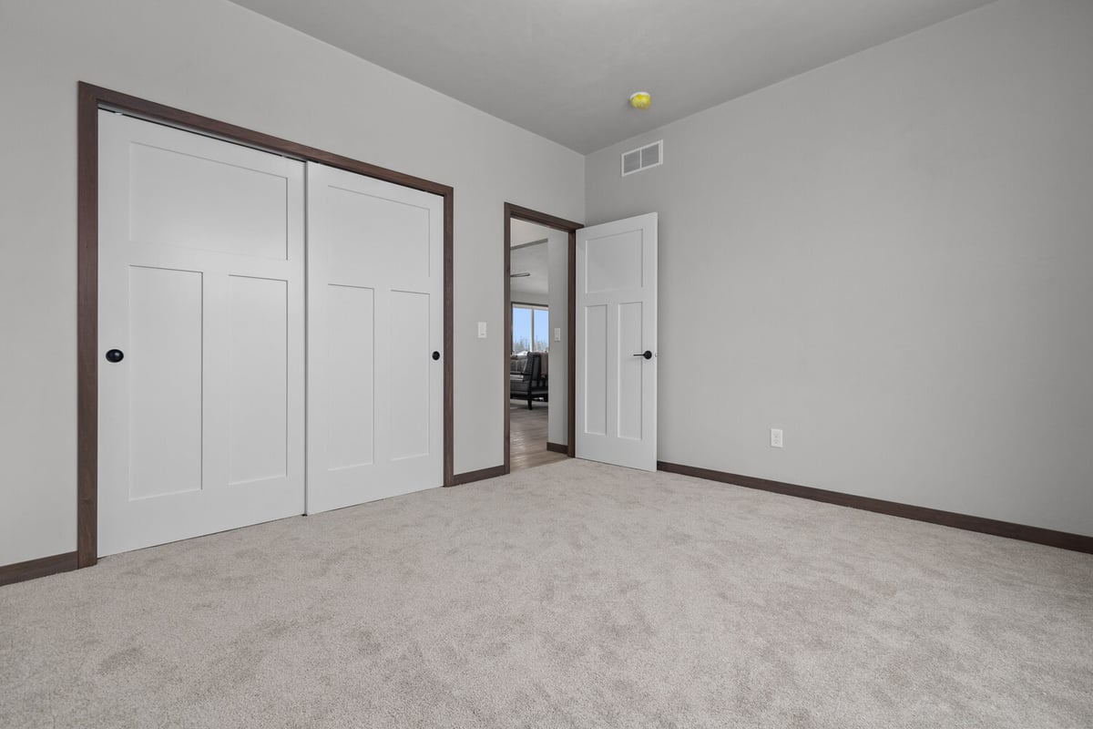 Finished bedroom with closet and neutral tones in a custom home by Midwest Design Homes