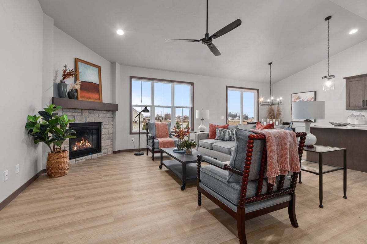 Open living room with fireplace and ceiling fan in a custom home by Midwest Design Homes