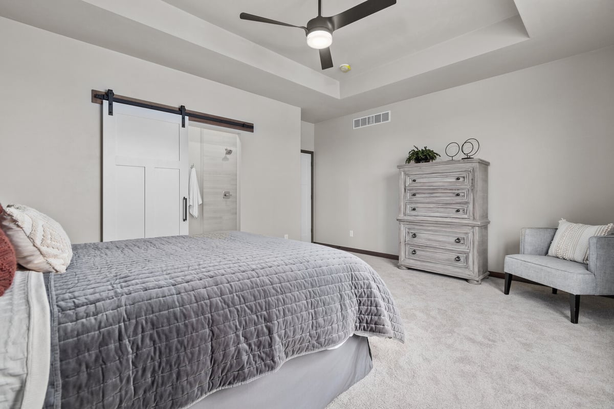 Primary bedroom with tray ceiling and fan by Midwest Design Homes in Kaukauna, WI