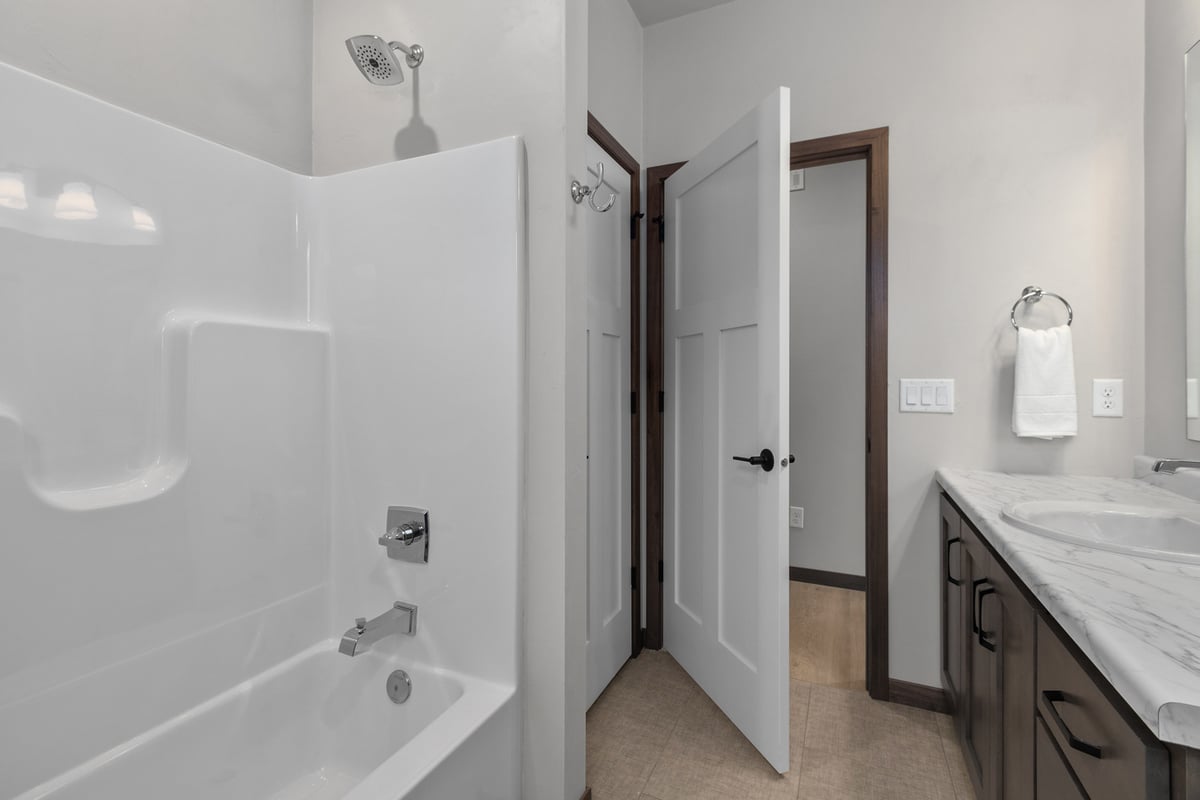 Tub and shower combo with white surround in a De Pere custom home by Midwest Design Homes