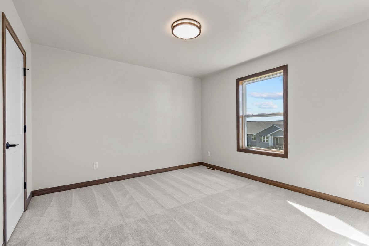 Carpeted bedroom with large window in Midwest Design Homes custom home, Wisconsin