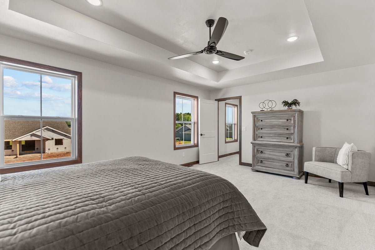 Custom home bedroom with large windows and ceiling fan by Midwest Design Homes, WI