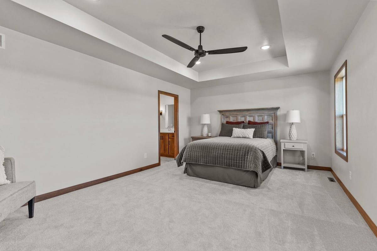 Master bedroom with ceiling fan and ensuite in Midwest Design Homes custom home
