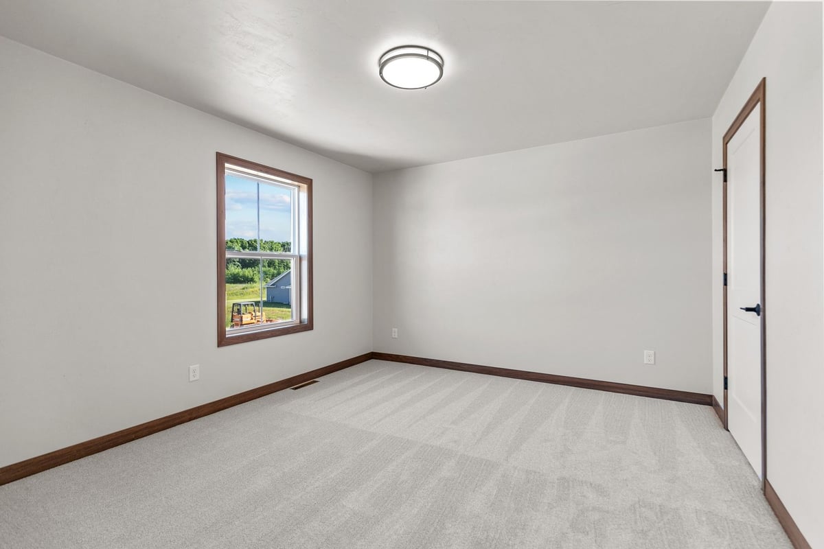 New bedroom space with window view in custom Wisconsin home by Midwest Design Homes