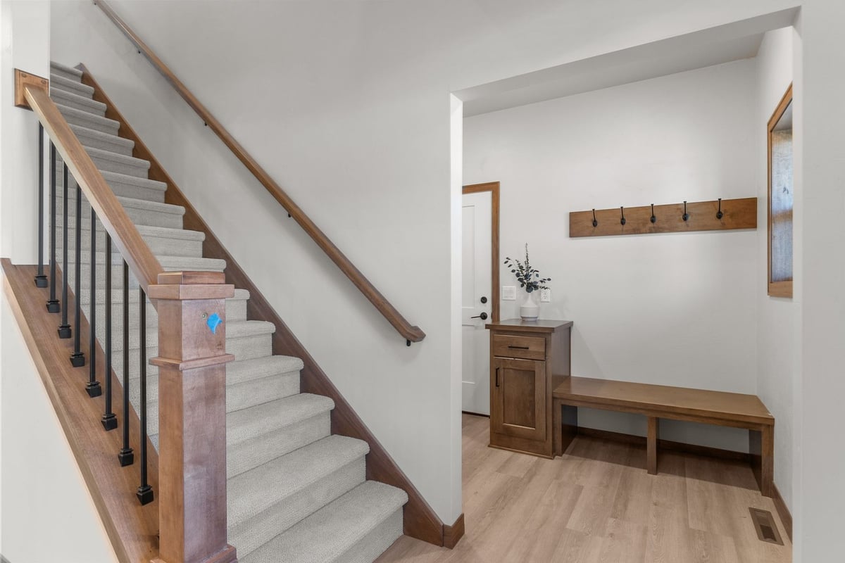 Wood-trim staircase beside mudroom bench in Midwest Design Homes custom home, WI