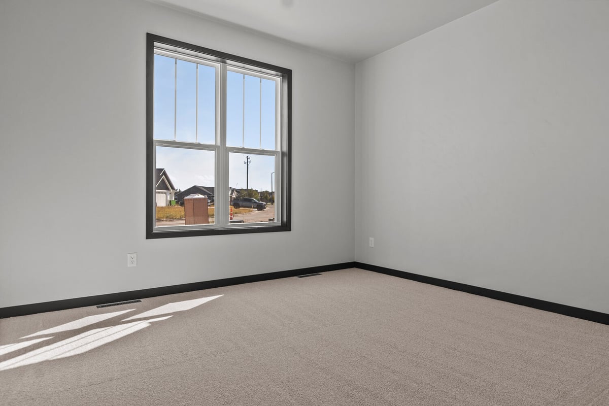 Bedroom with large window and soft carpet by Midwest Design Homes in Bellevue, WI