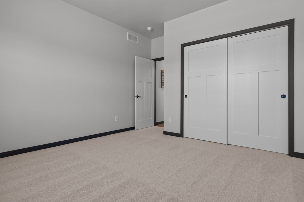 Empty bedroom with carpet and double doors by Midwest Design Homes in De Pere, WI