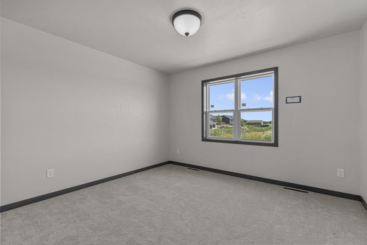 Bedroom with carpet and large window in custom home by Midwest Design Homes