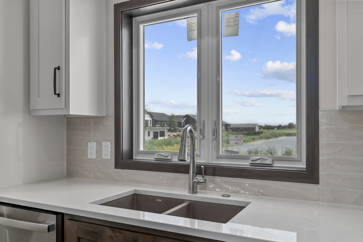 Kitchen sink under window with pond view in custom WI home by Midwest Design Homes