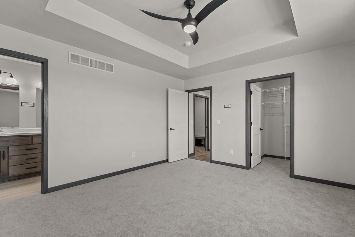 Primary bedroom with ceiling fan and walk-in closet by Midwest Design Homes in WI