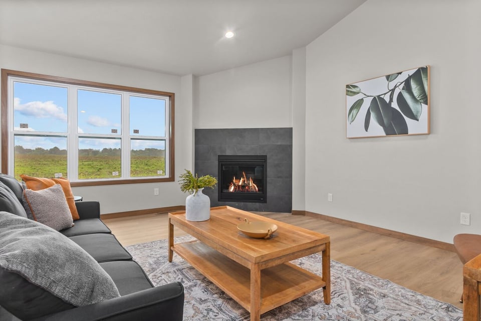 Living room with black fireplace and large window by Midwest Design Homes in Fox Cities, WI