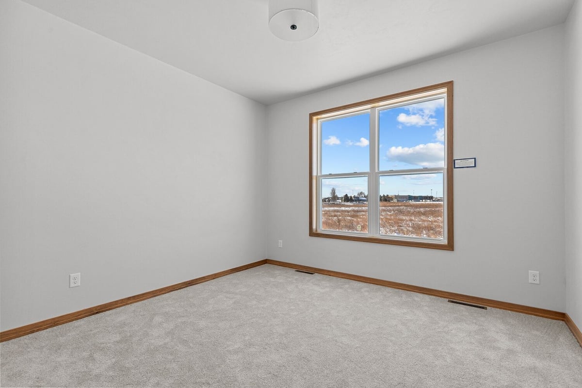 Carpeted bedroom with large window by Midwest Design Homes in Greenville Wisconsin