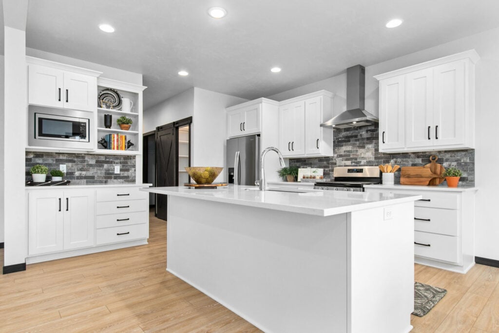 Bright white kitchen with large island, wood floors, stainless appliances, and tile backsplash in Northeast Wisconsin