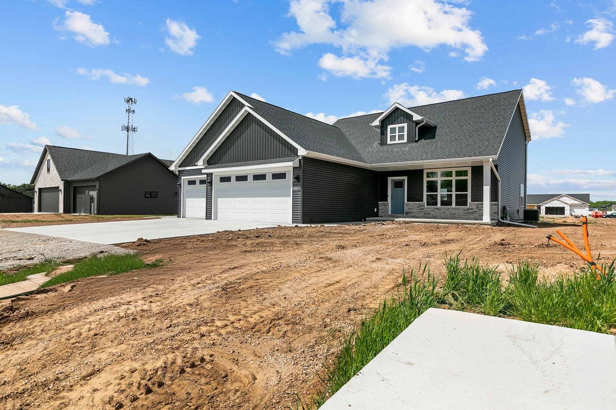 Angled front view of modern black home with stone accents and spacious driveway in Appleton, WI