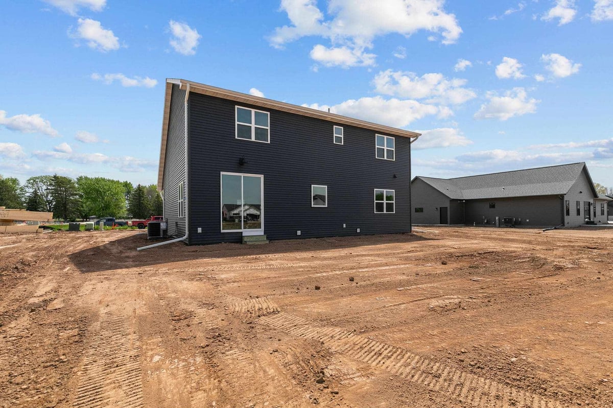 Back exterior of modern black two-story home with large dirt yard in Appleton, WI subdivision