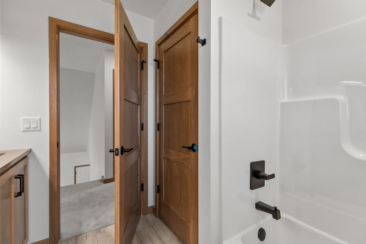 Bathroom with tub shower combo, wood doors, and black hardware in Appleton, WI
