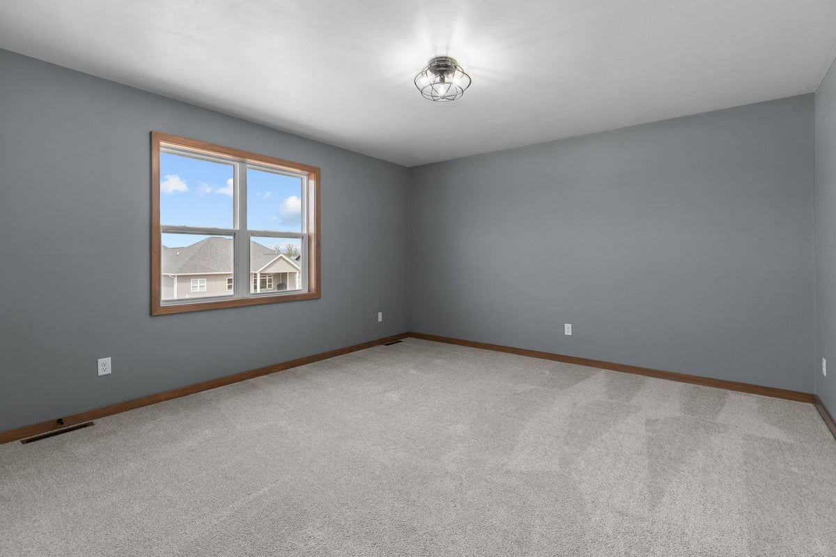 Bright bedroom with gray walls, soft carpet, and large window in a new Appleton, WI home
