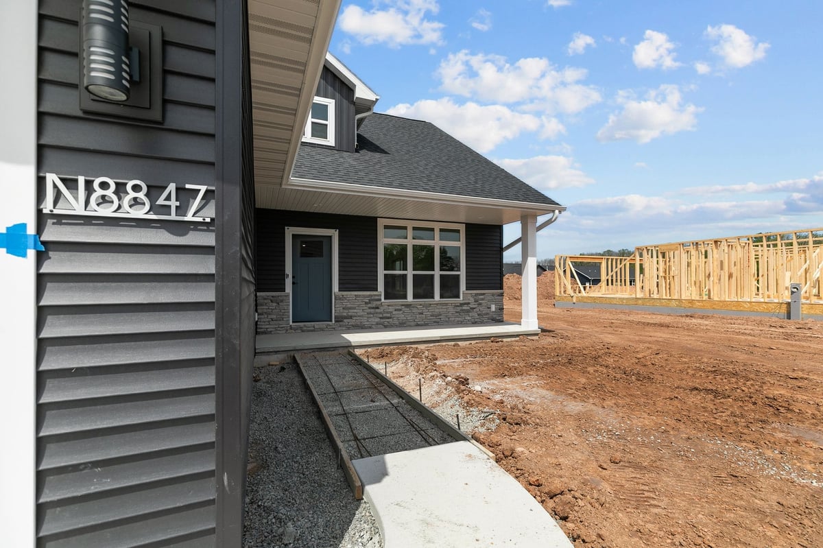 Covered patio entry with dark siding and stone accents on a new home in Appleton, WI
