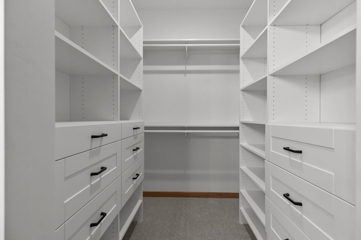 Custom walk-in closet with white shelving and built-in drawers in Appleton, WI