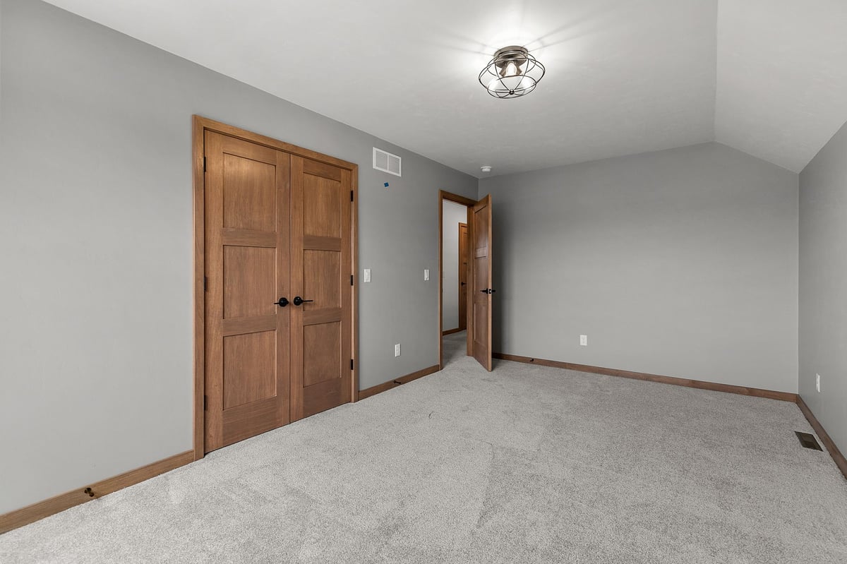Modern bedroom with gray walls, carpet, and wood trim in a newly built Appleton, WI home