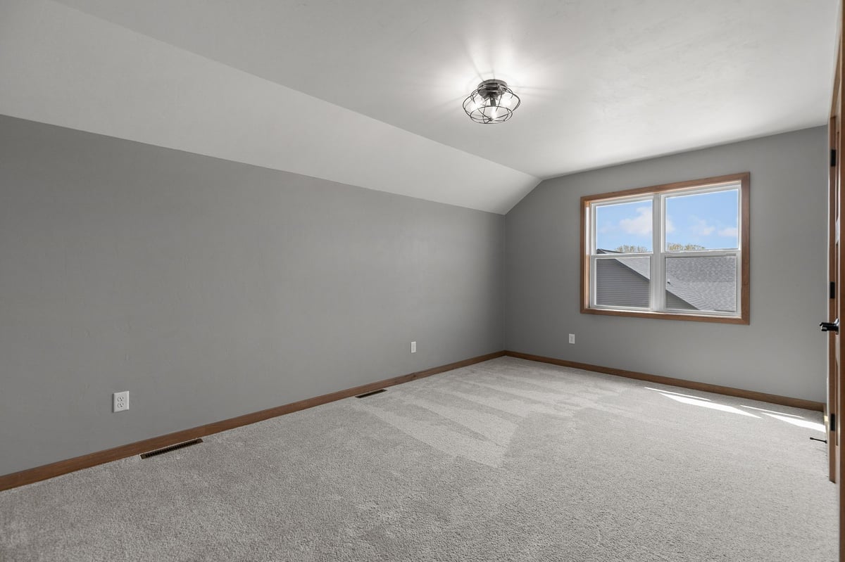 Modern bedroom with gray walls, plush carpet, and ceiling fan in a newly built Appleton, WI home