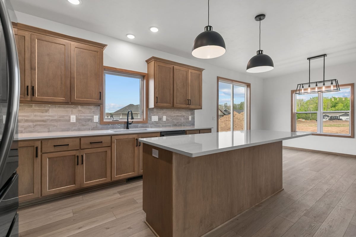 Modern kitchen with wood cabinetry, large island, and pendant lighting in Appleton, WI