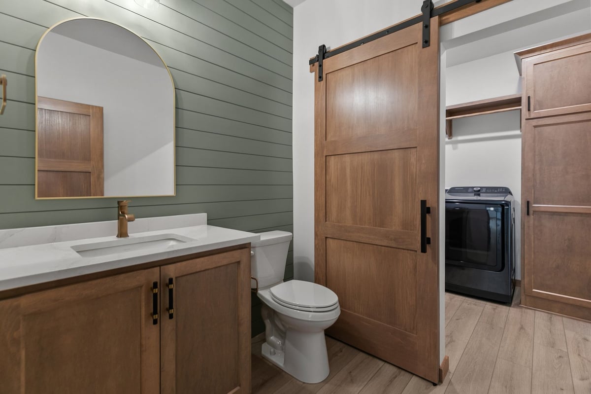 Modern powder room with green accent wall and barn door laundry area in Appleton, WI