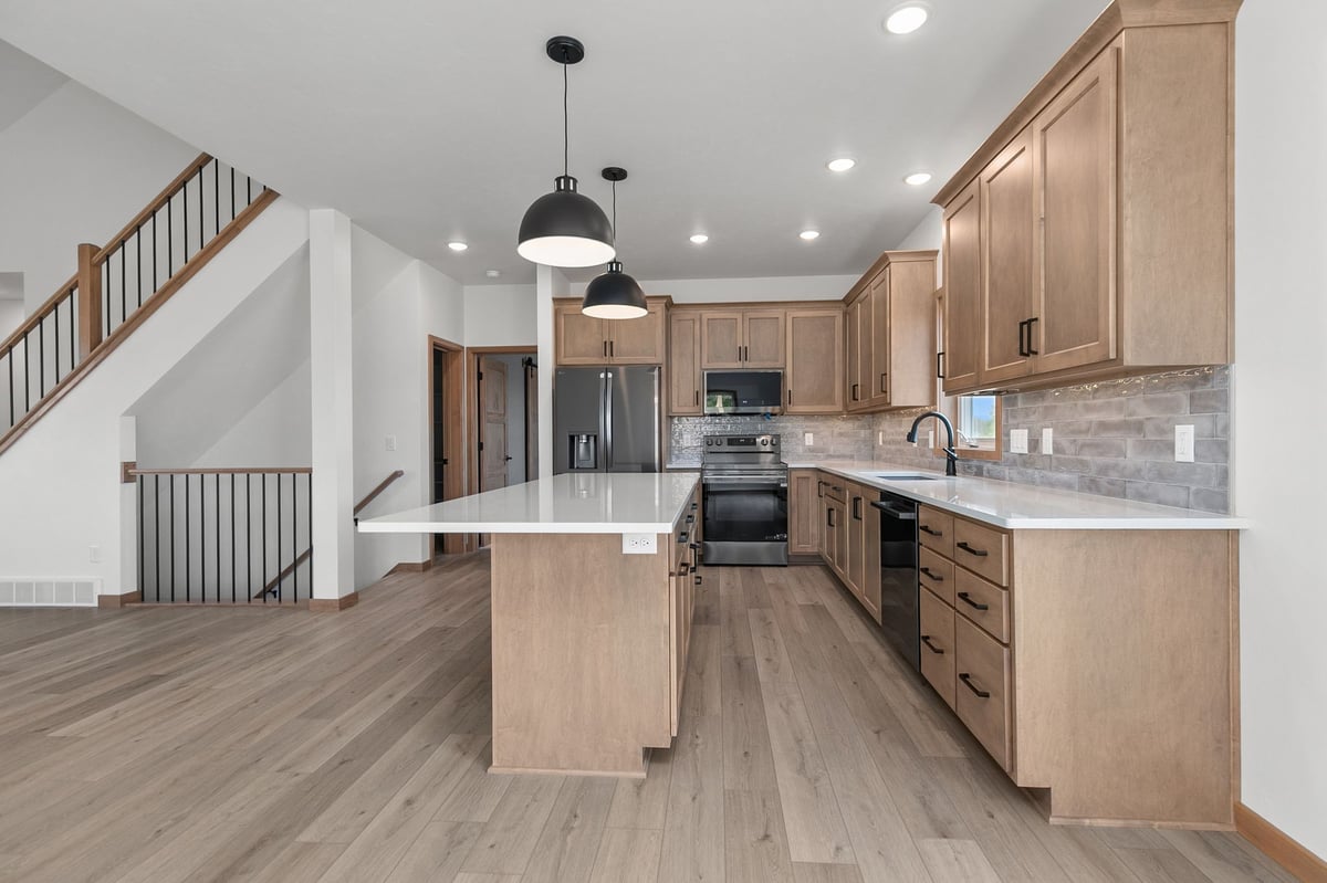 Open kitchen with quartz island, wood cabinets, and black fixtures in Appleton, WI